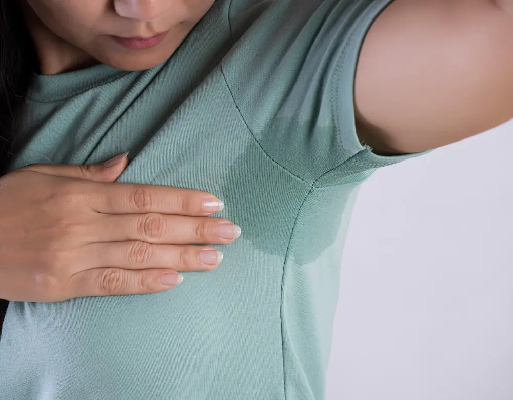 Ein deutlich sichtbarer Schweißfleck unter dem Arm einer Frau